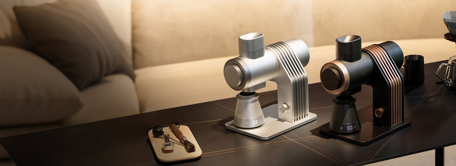 Two modern coffee grinders on a wooden surface with a blurred background